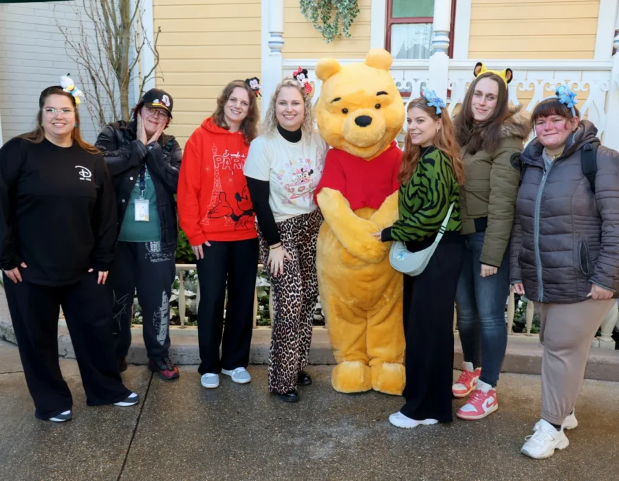 Acht Pixies met Disney-oren poseren met Winnie de Poeh in Disneyland Parijs